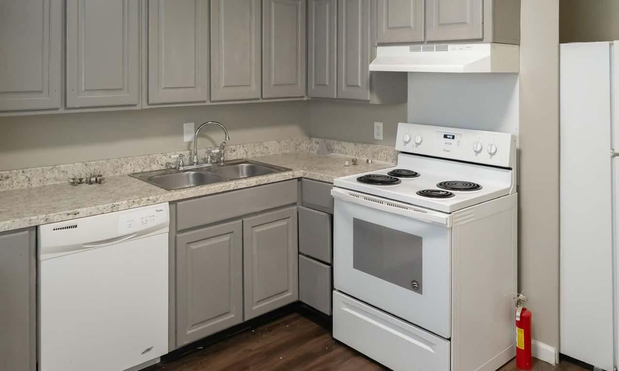 Small white kitchen with cabinets, sink, dishwasher, stove, and granite countertops