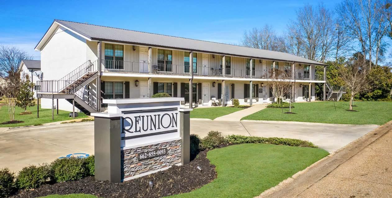 Reunion hotel sign in front of a two-story beige building with balconies and a driveway