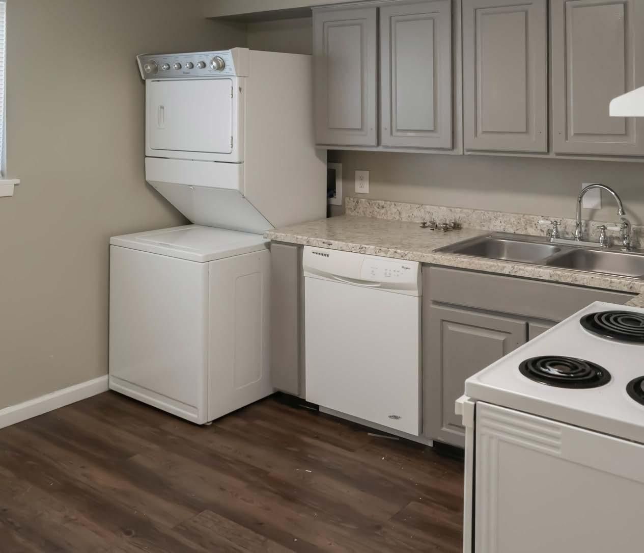 Small beige kitchen with white appliances, gray cabinets, dark wood floor, and a sink by the counter.