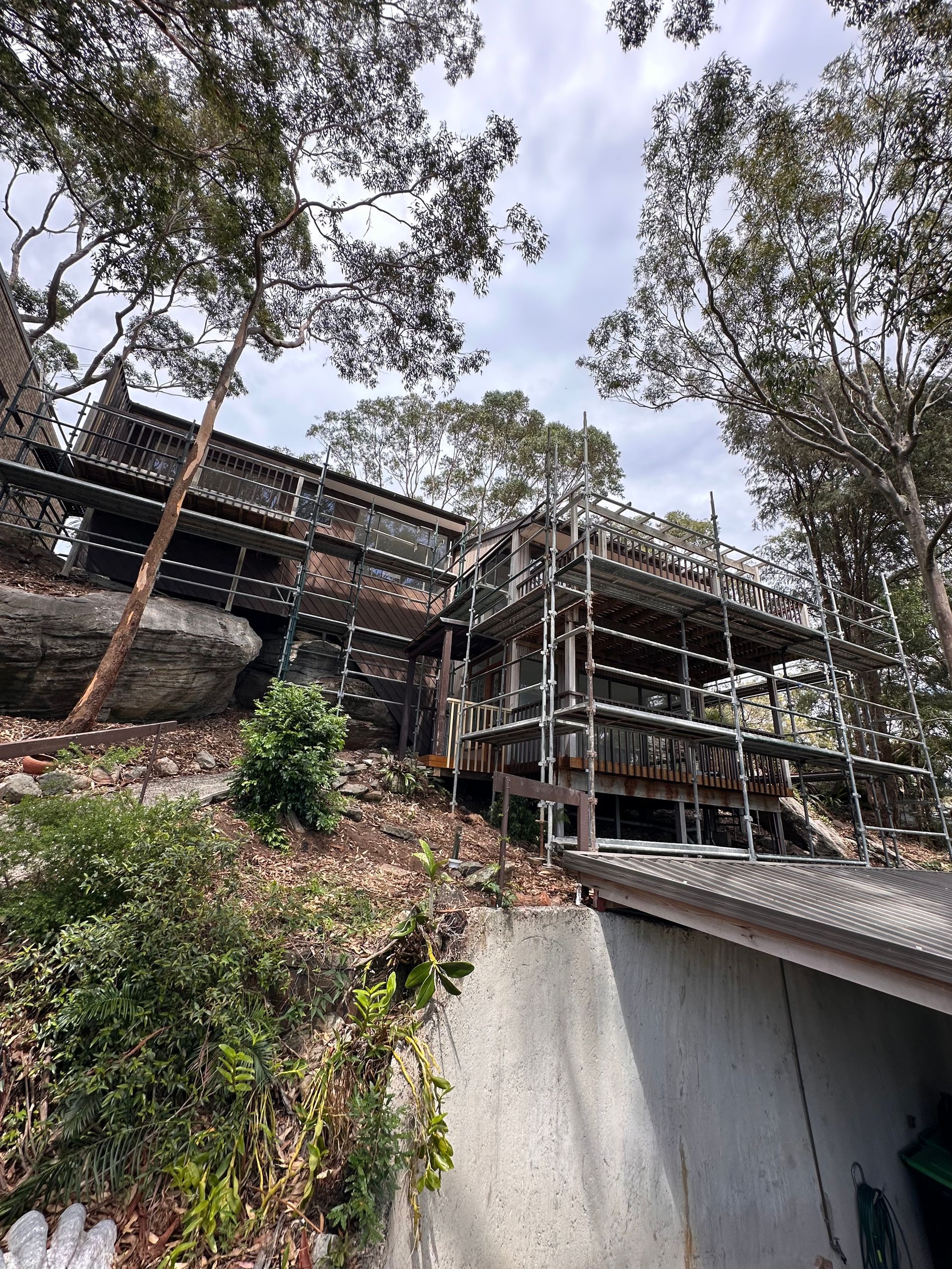 Scaffold built over natural rockface to provide access for timber deck repairs and external house painting.