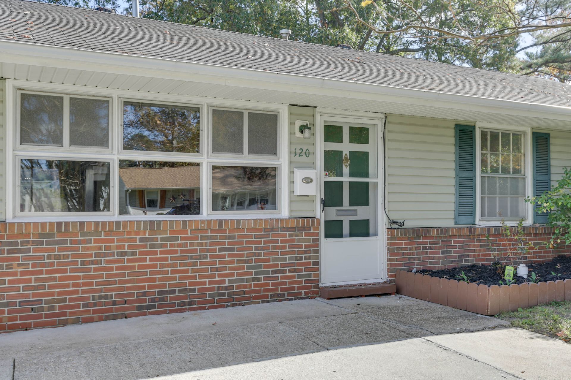 Single-story brick-and-siding house exterior with a white front door and large windows