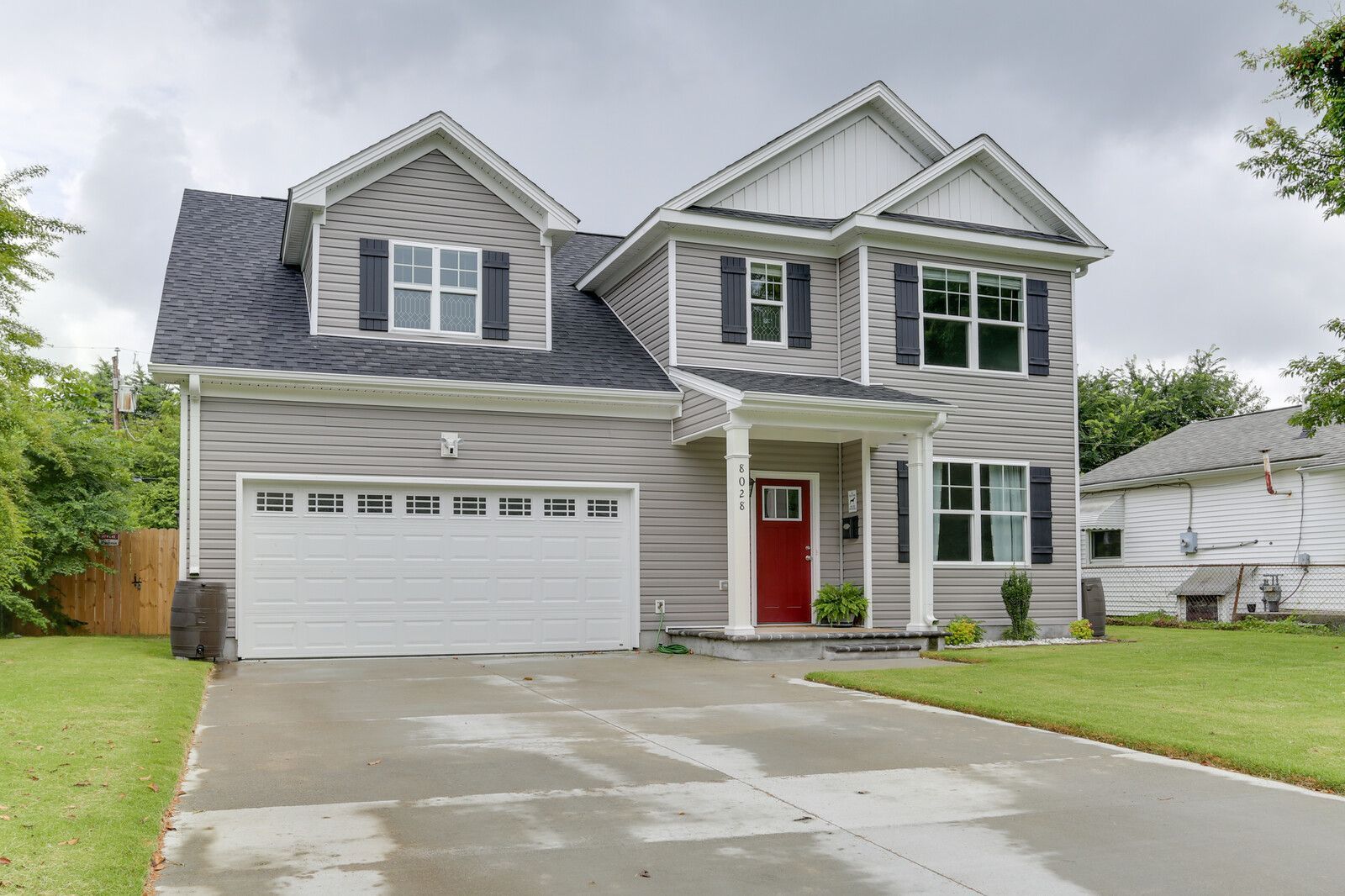 Suburban two-story gray house with white trim, red front door, and attached two-car garage