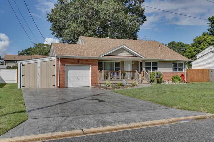 Suburban single-story house with garage, driveway, and front lawn under a blue sky