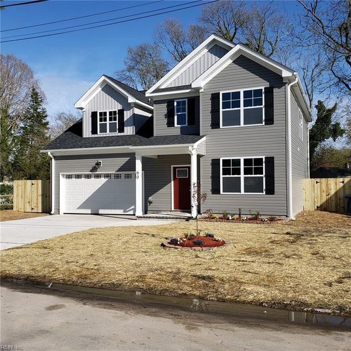 New two-story gray house with white trim, double garage, and small front lawn under clear blue sky