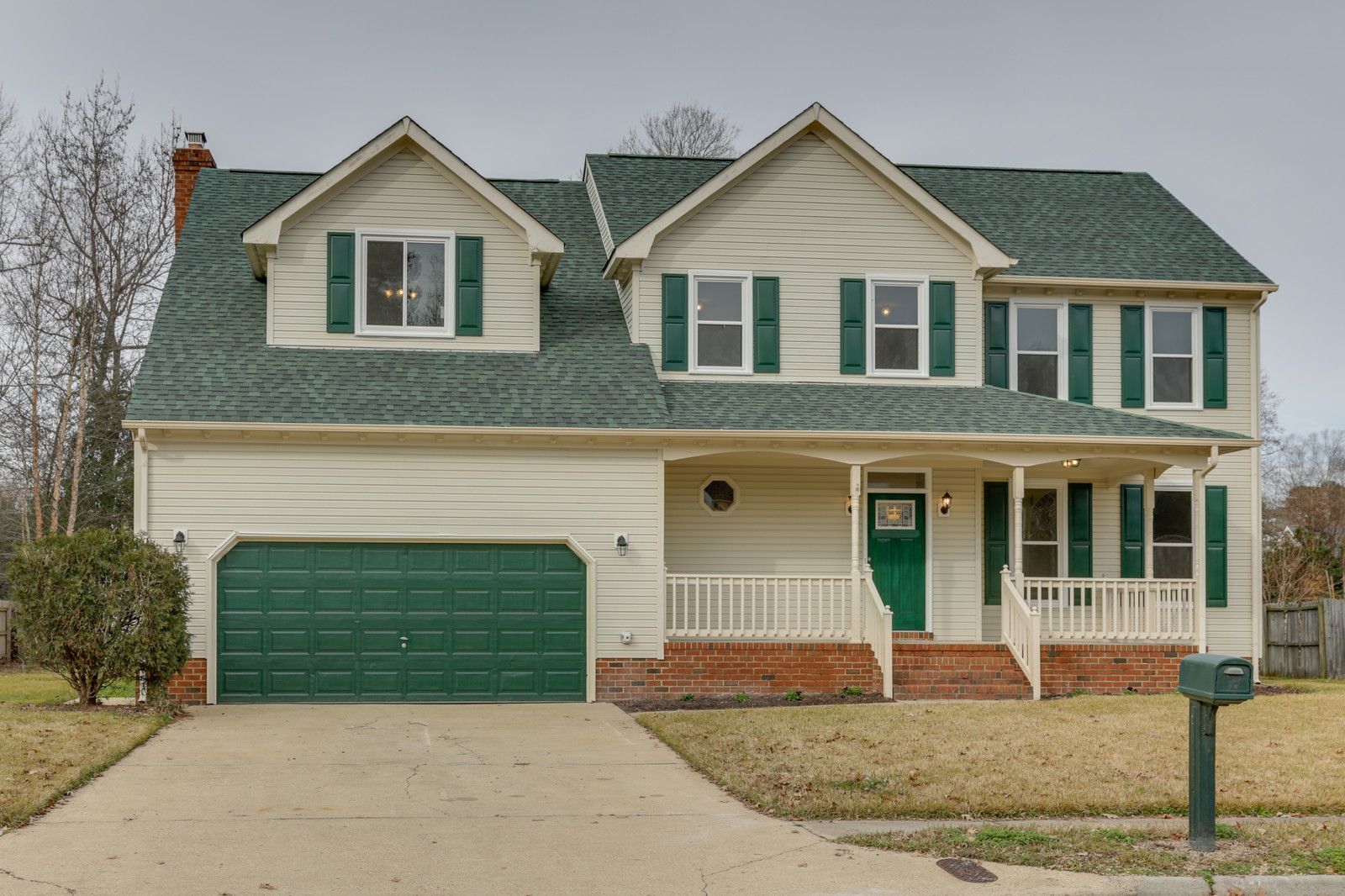 Two-story suburban house with green roof, white trim, and attached green garage under an overcast sky
