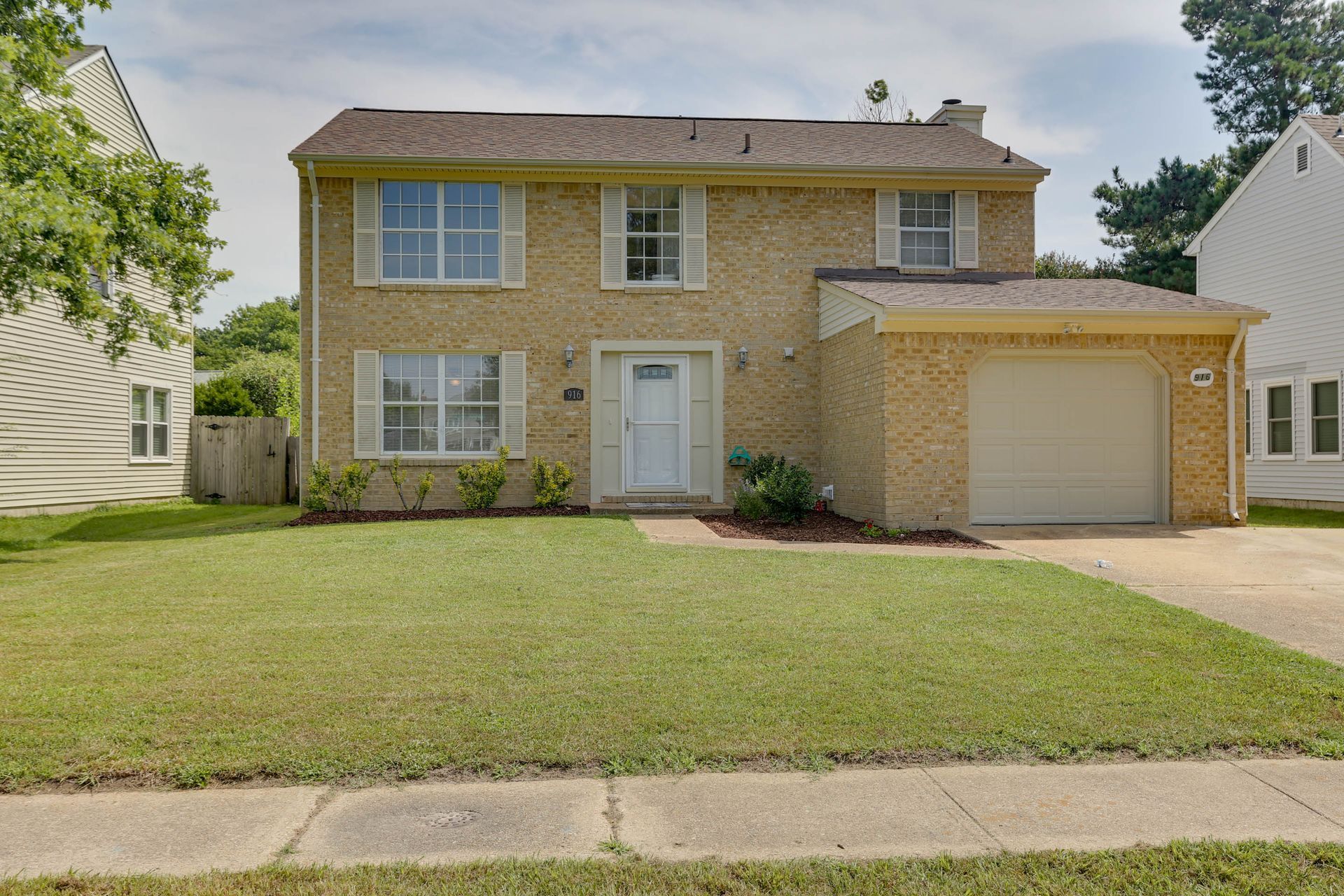 Two-story brick house with a front lawn and attached garage on a suburban street