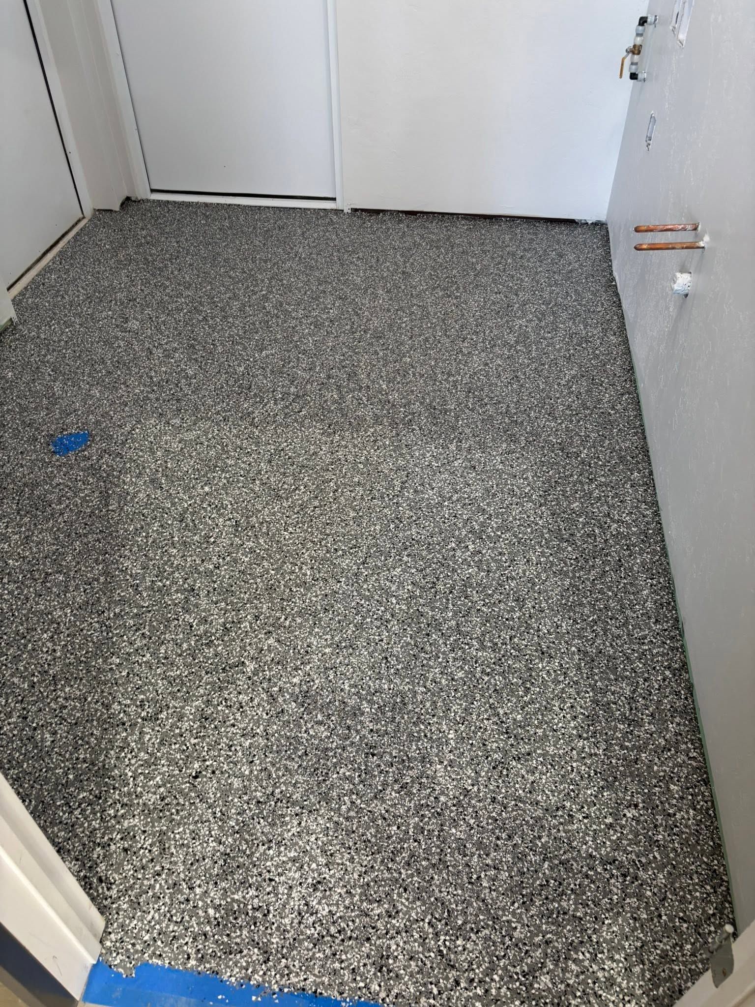 Small empty room with speckled gray floor and white walls, viewed from the doorway.