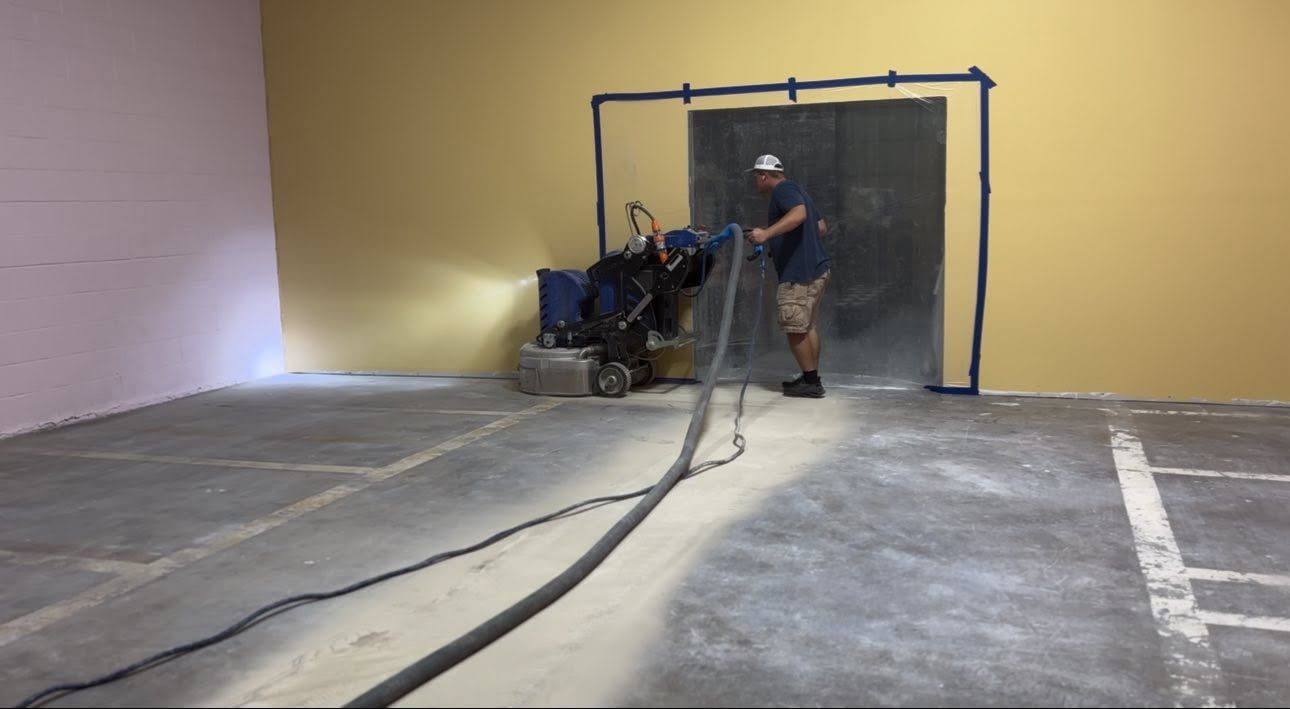Person spraying paint inside a large indoor space near a black-framed doorway