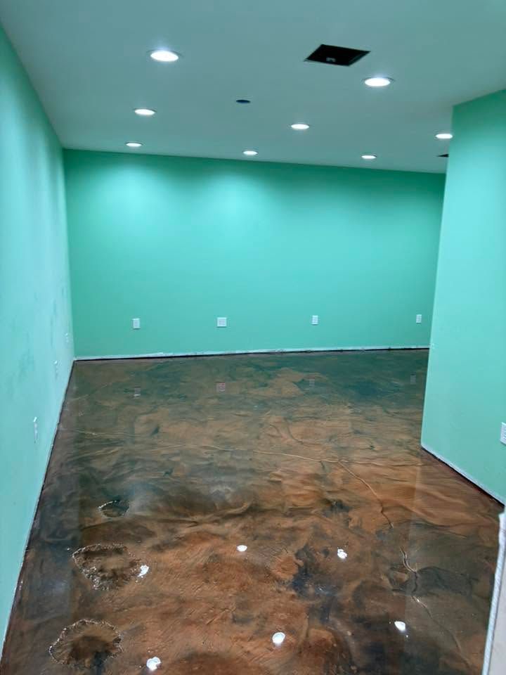 Empty mint-green room with bare brown floor and recessed ceiling lights