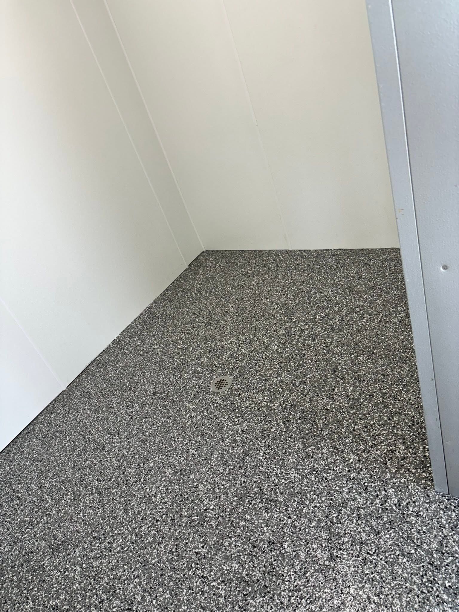 Empty white corner with speckled gray carpet and a partially open door