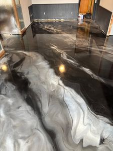 Swirling black, white, and gray epoxy floor in a modern hallway with glossy reflections