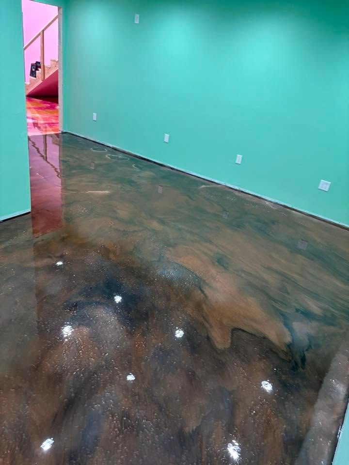 Empty room with turquoise walls and a glossy dark stained concrete floor, viewed from a doorway