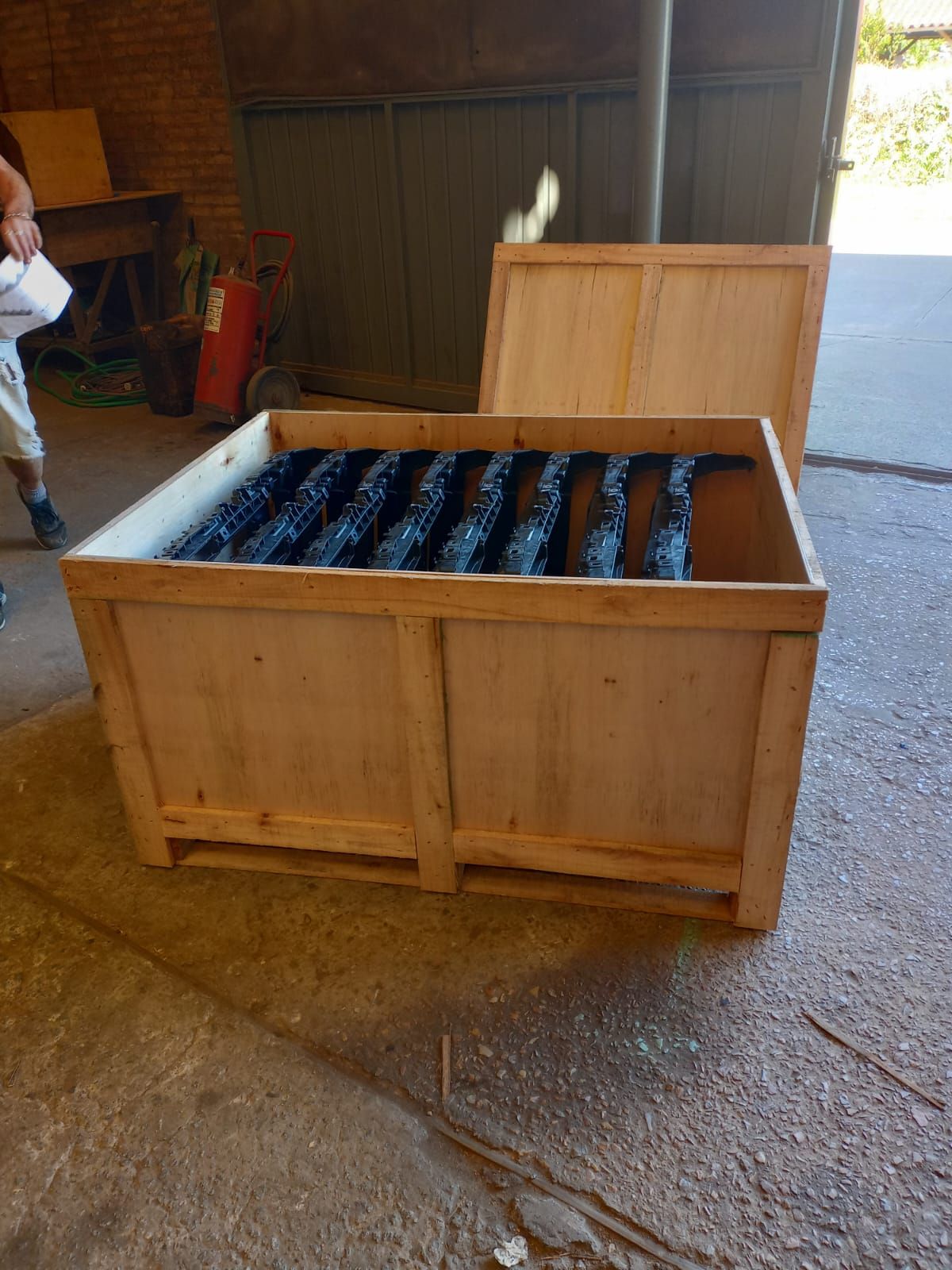 En un taller, una persona se encuentra junto a una caja de madera abierta