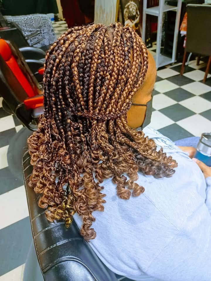 A woman with braids and curly hair is sitting in a chair.