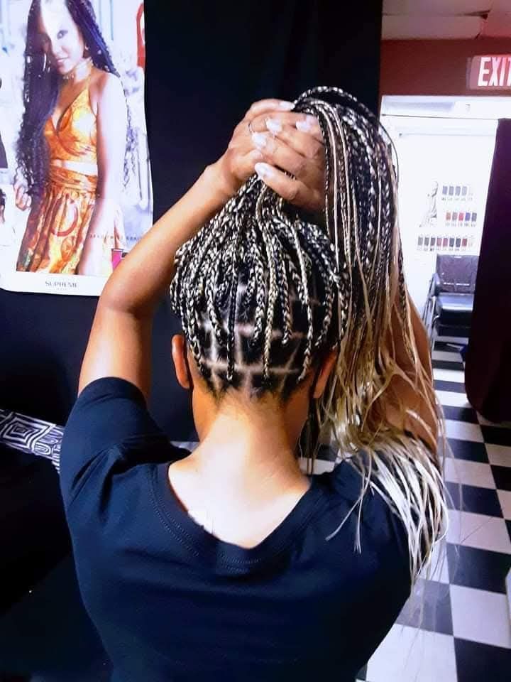 A woman with braids is standing in front of an exit sign