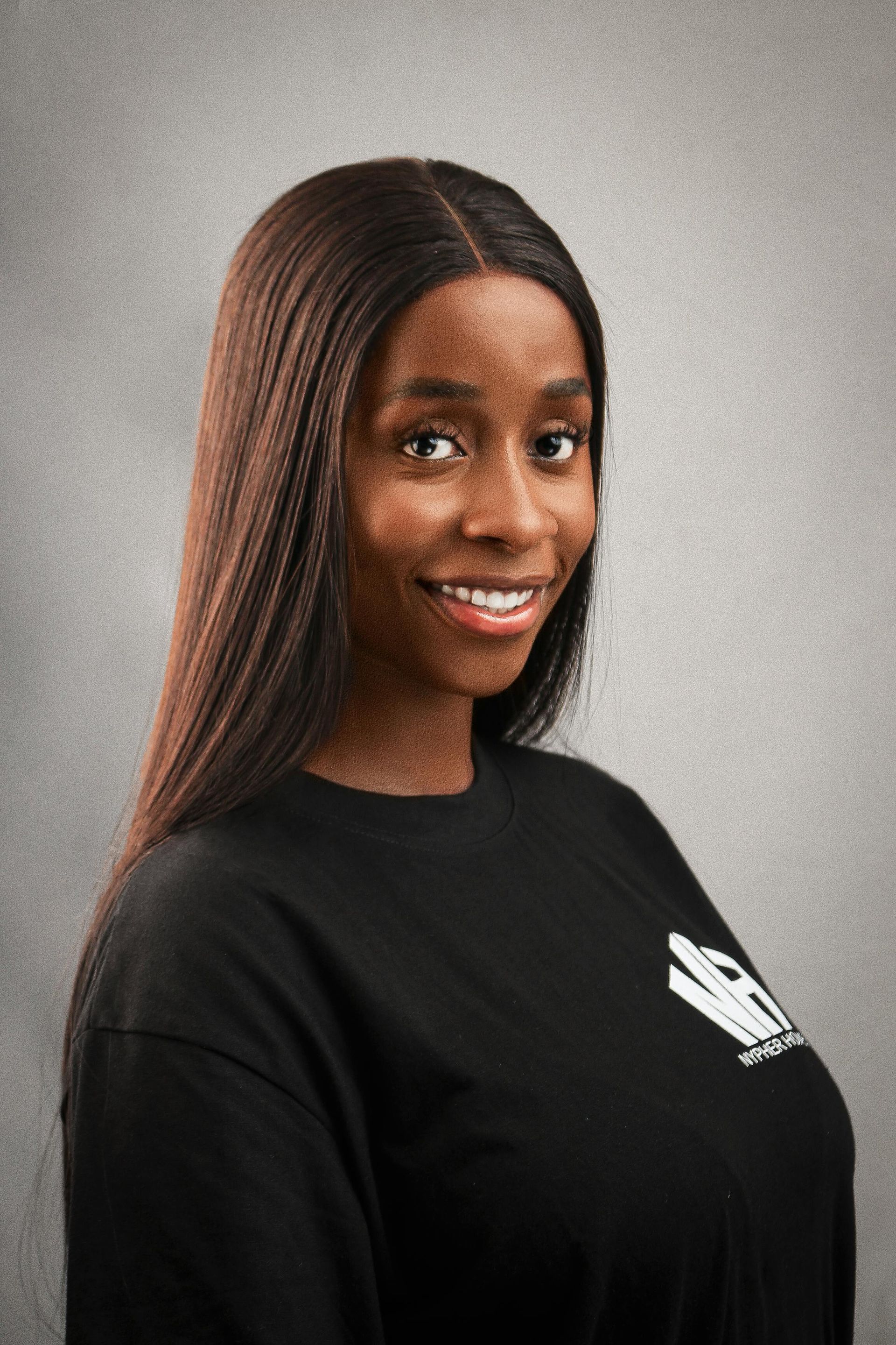 Smiling woman with long braids in a black shirt against a gray background