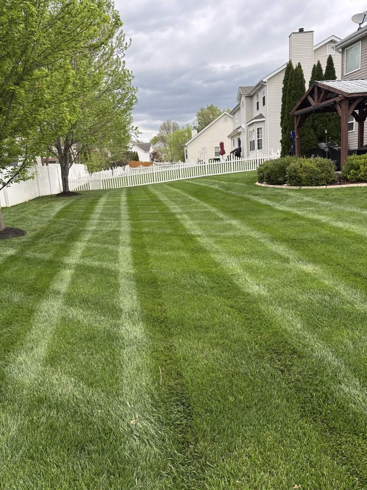 Freshly mowed green lawn beside white houses under a cloudy sky