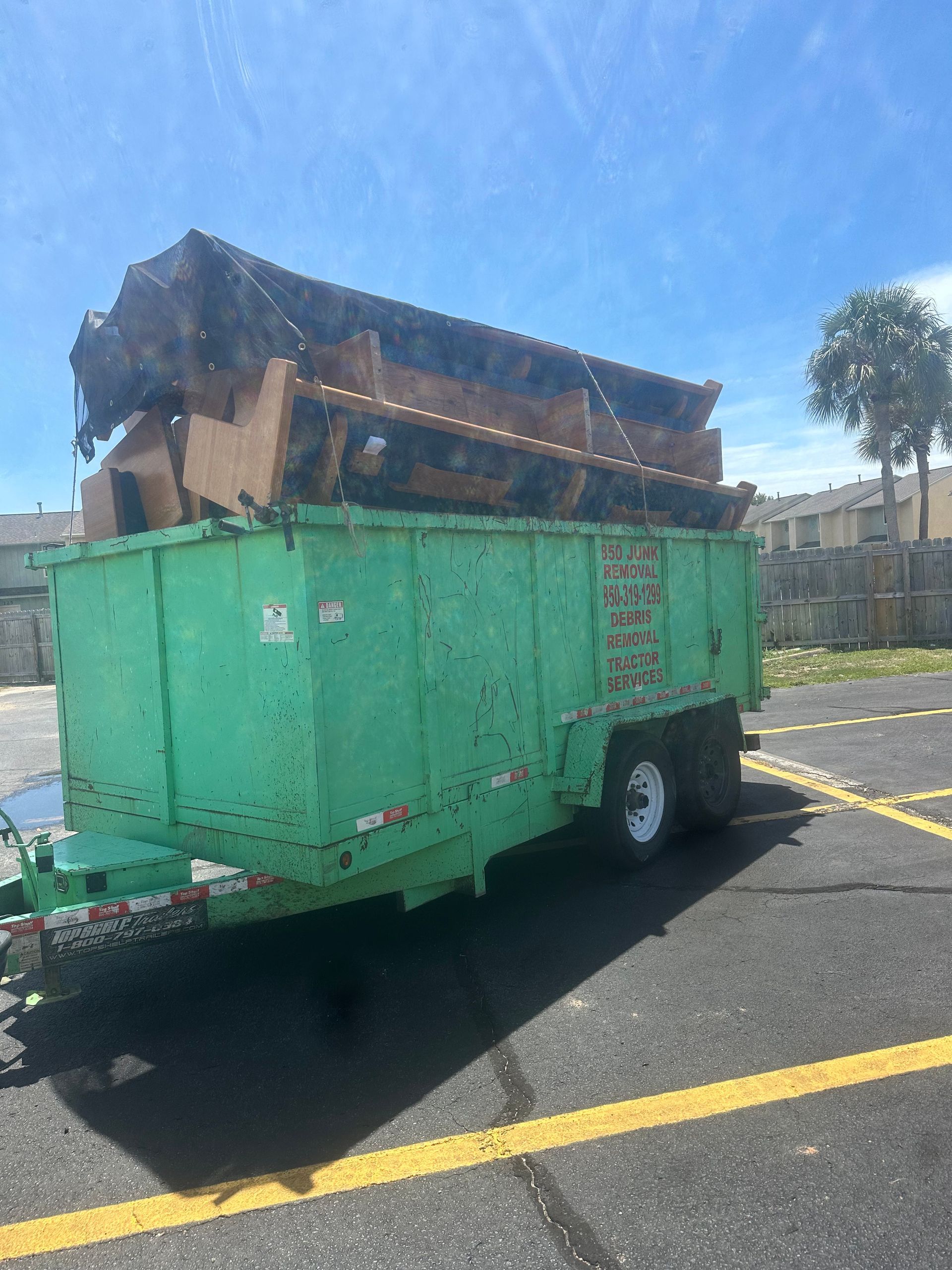 A green dumpster trailer is parked in a parking lot.