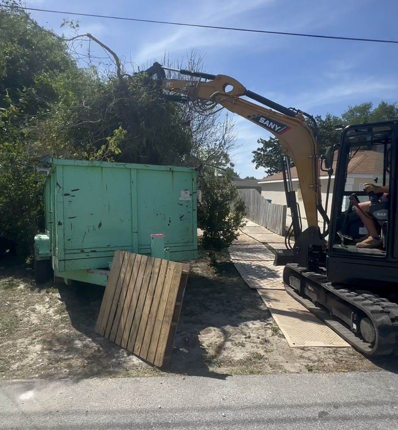 Mini excavator with a thumb loading fallen tree limbs into our trailer