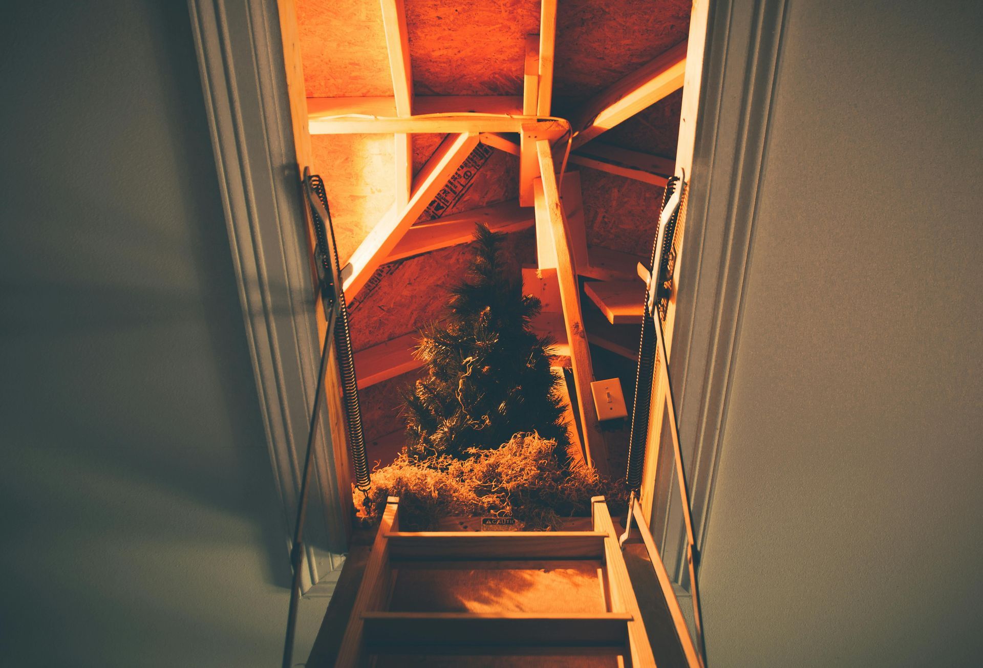 A wooden staircase leading up to an attic with a christmas tree in it.
