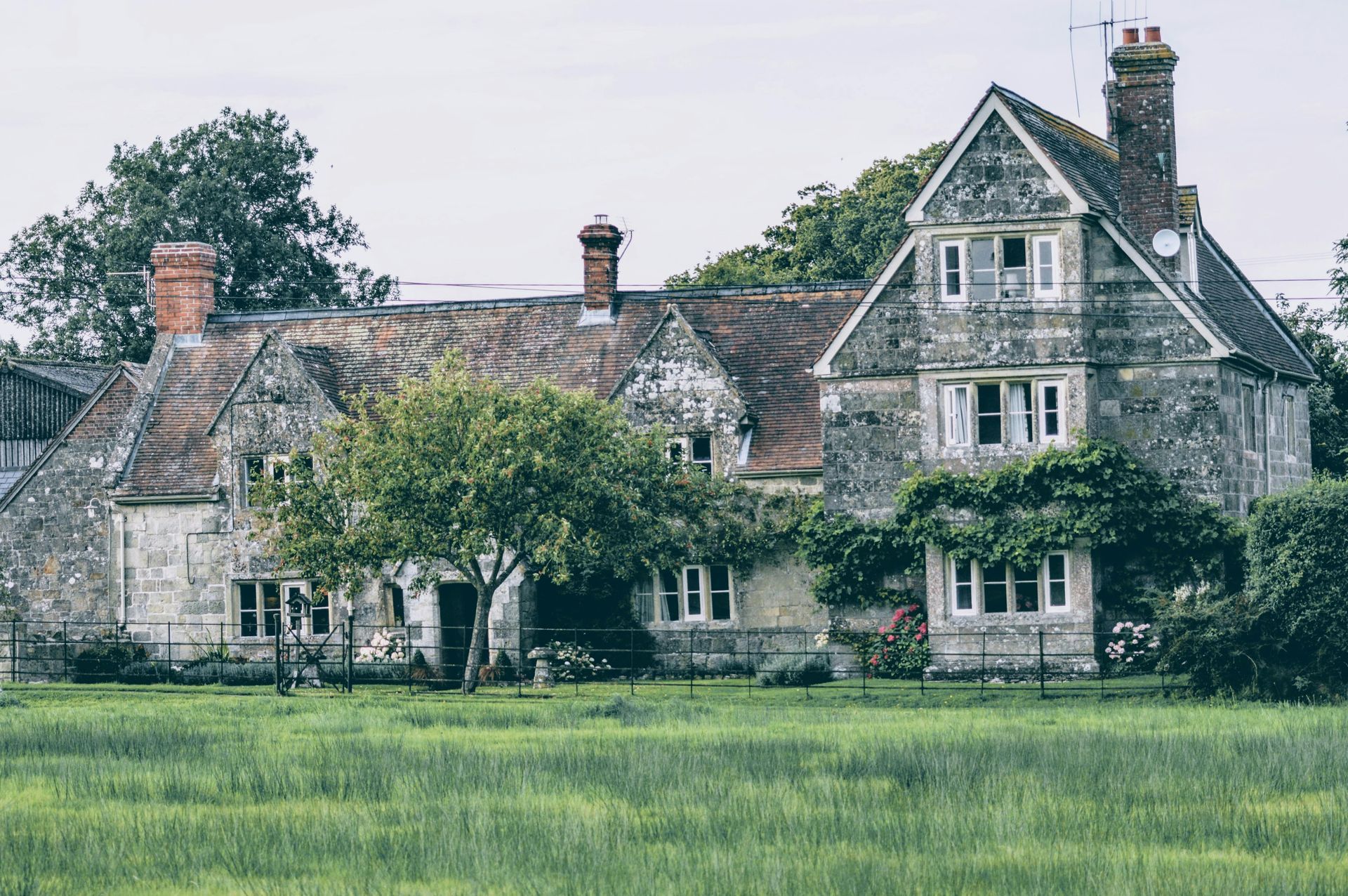 A large house is sitting in the middle of a grassy field.