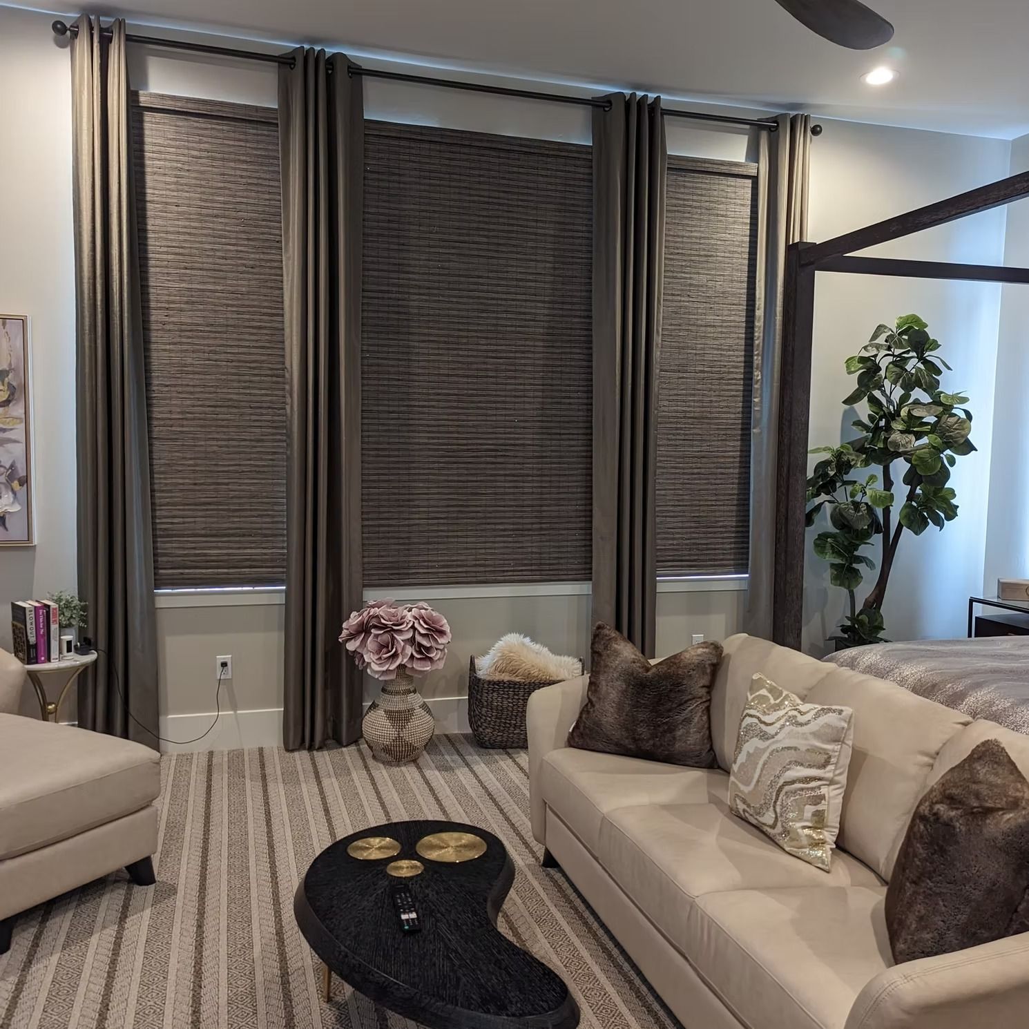 Modern living room with beige sofas, dark woven window shades, and a black coffee table on a striped rug