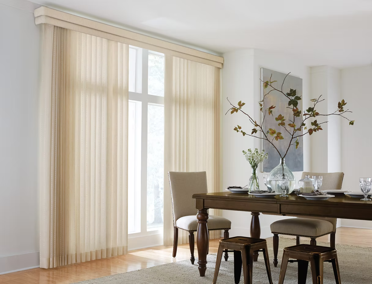 Bright dining room with sheer curtains, wooden table, and vase of branches by a large window