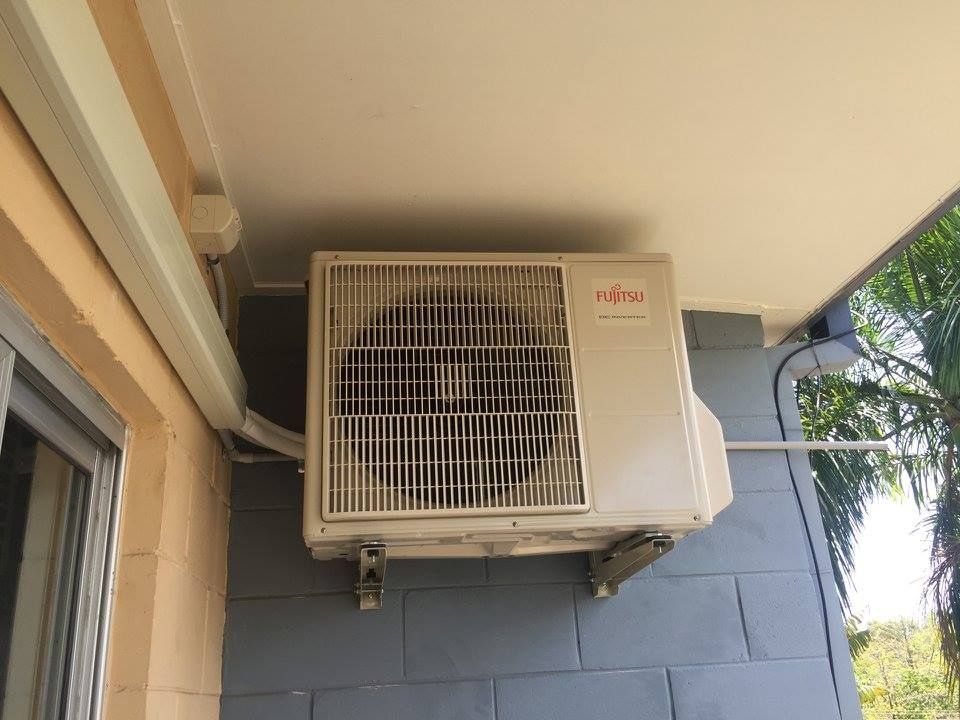 Fujitsu air conditioning unit mounted on a grey brick wall, under a white eave. — Active Airconz in Burketown, QLD