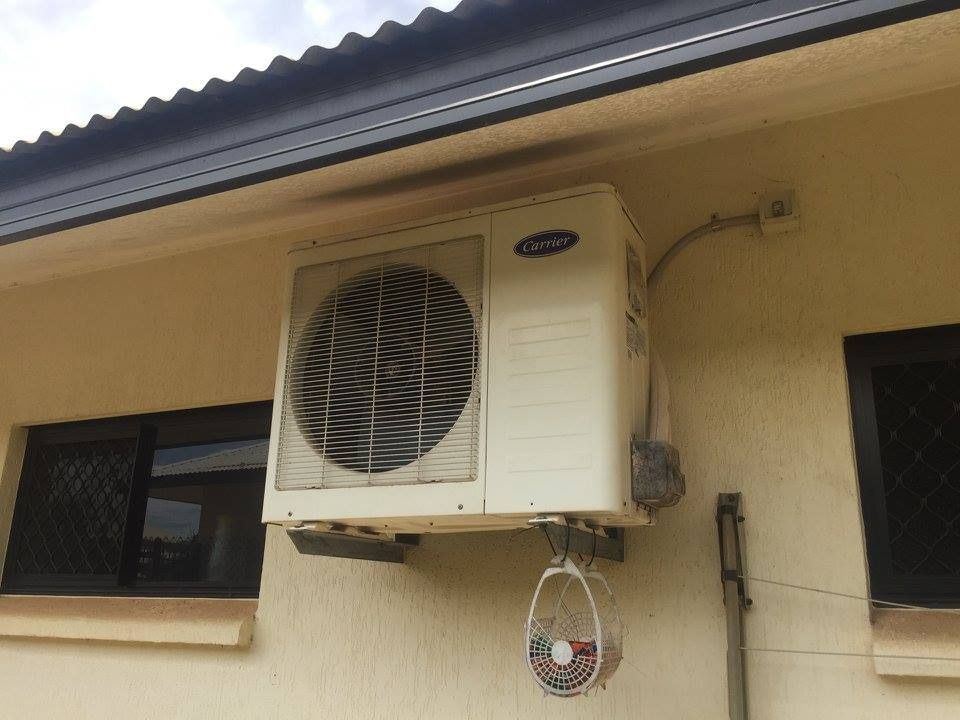 Exterior Carrier Air Conditioner Unit Mounted on a Beige Wall — Active Airconz in Brisbane, QLD