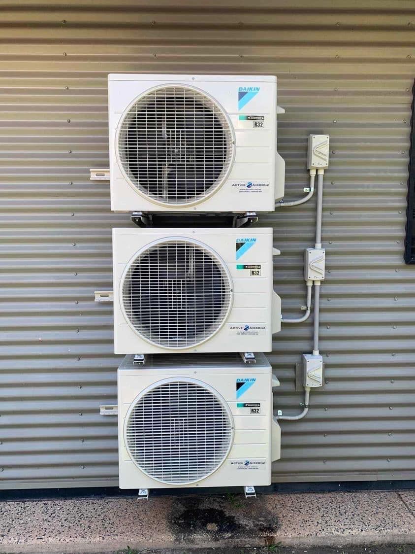 Three White Air Conditioning Units Stacked on A Metal Wall — Active Airconz in Perth, QLD