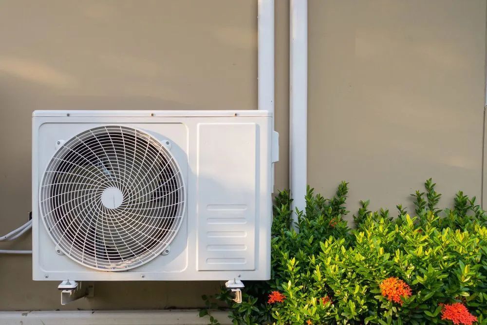 White Air Conditioner Unit Mounted on a Beige Wall — Active Airconz in Burketown, QLD