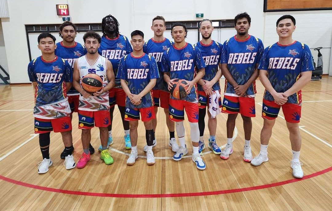 Basketball team in blue and red uniforms posing on a gym court with a basketball in hand