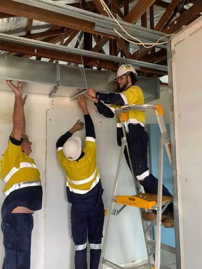 Three Construction Workers Installing Ductwork Inside a Building — Active Airconz in Rockhampton, QLD