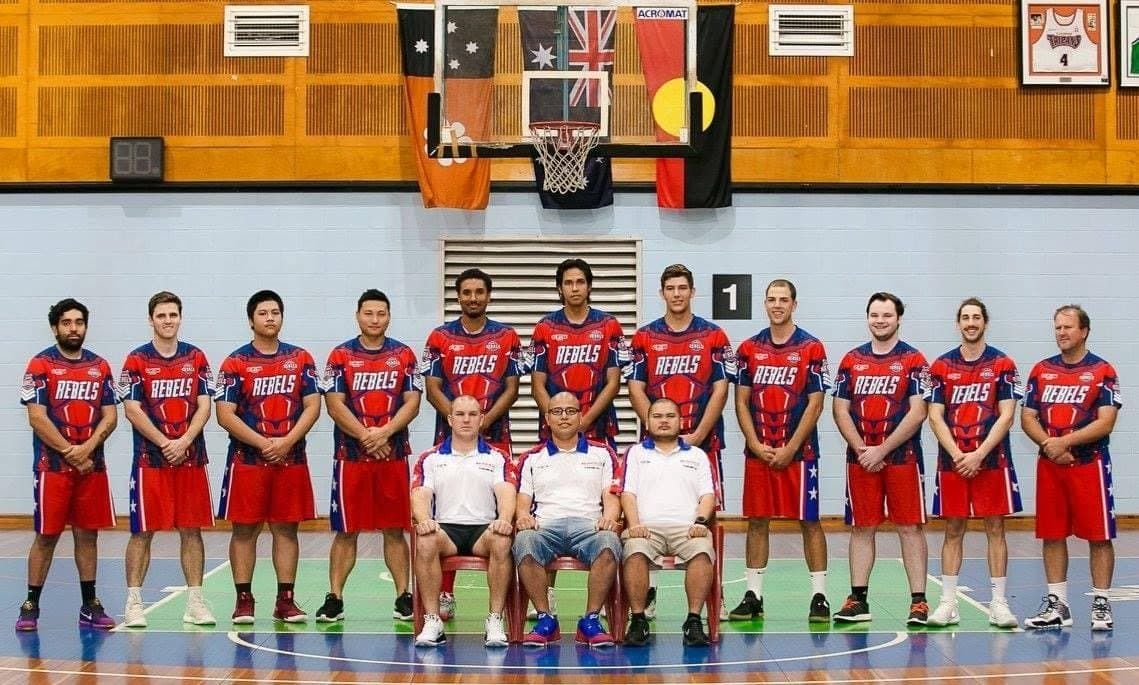Two basketball teams pose for a group photo in an indoor gym, wearing red and white uniforms. — Active Airconz in Winnellie, NT