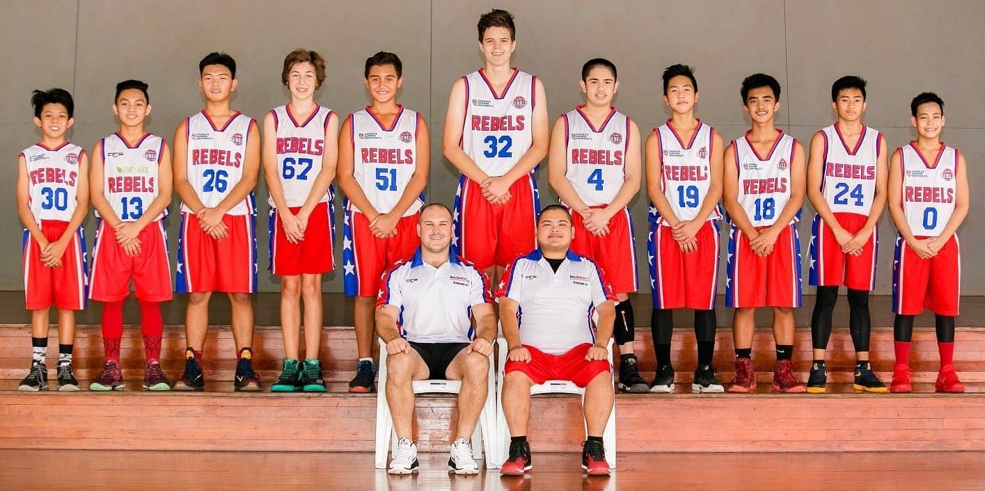 Group of basketball players and coaches posing in red and white uniforms on a gym bleacher stairway — Active Airconz in Winnellie, NT