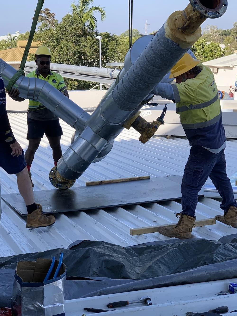 Workers Installing Insulated Pipes on a Rooftop, Using a Crane — Active Airconz in Brisbane, QLD