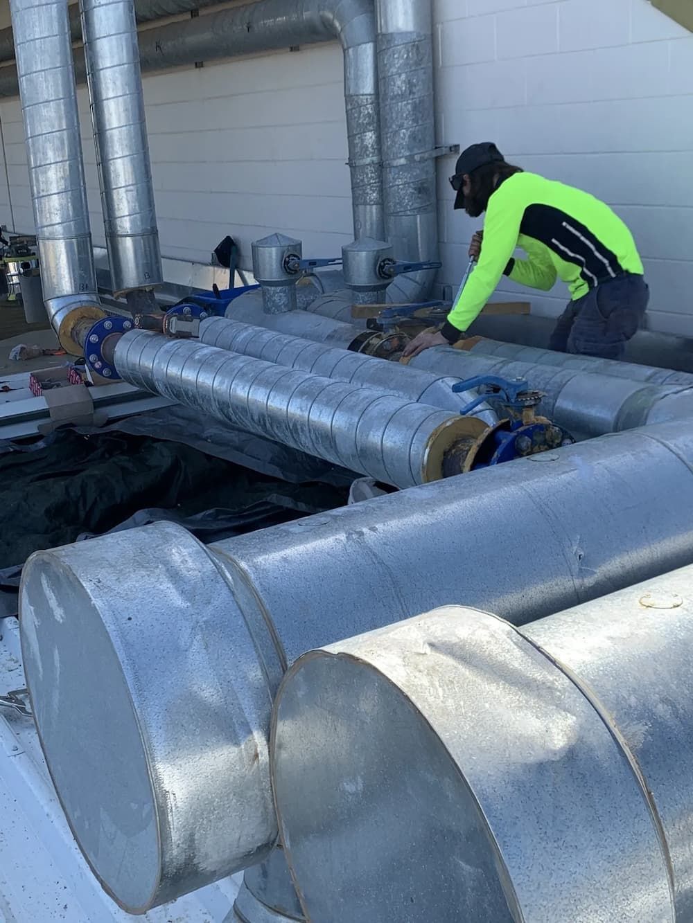 Person in neon green shirt working on insulated pipes outside. — Active Airconz in Toowoomba, QLD