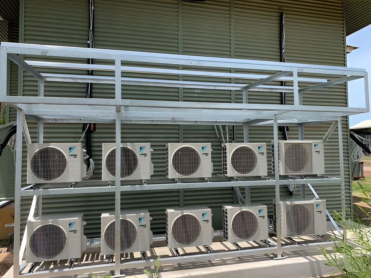 White metal rack holding eleven air conditioning units against a corrugated metal wall. — Active Airconz in Townsville, QLD