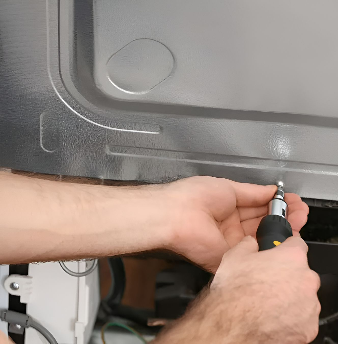 A Pair of Hands Uses a Screwdriver to Secure a Screw Into the Metal Panel of A Home Appliance — Active Airconz in Winnellie, NT