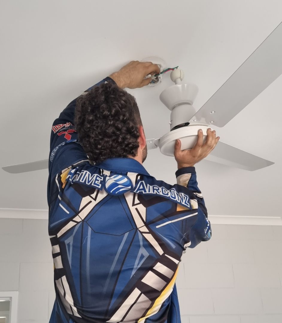 Man in Blue Jumpsuit Installing a White Ceiling Fan — Active Airconz in Winnellie, NT