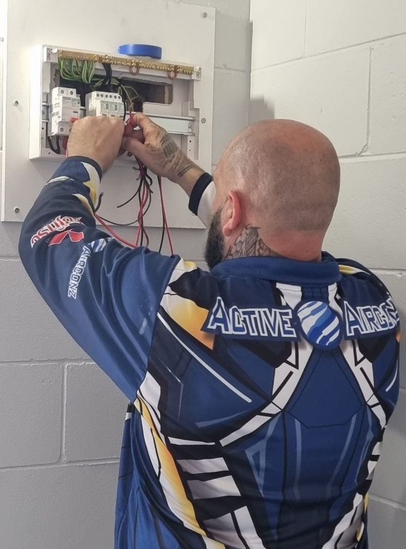 Electrician Wiring a Fuse Box on a White Brick Wall — Active Airconz in Winnellie, NT