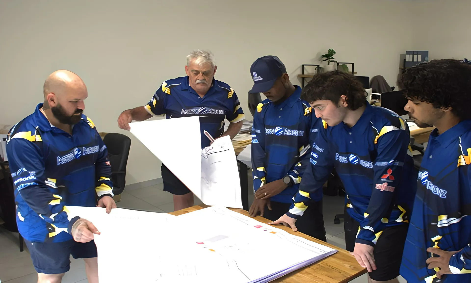 People in Blue Shirts Gather Around a Table — Active Airconz in Winnellie, NT