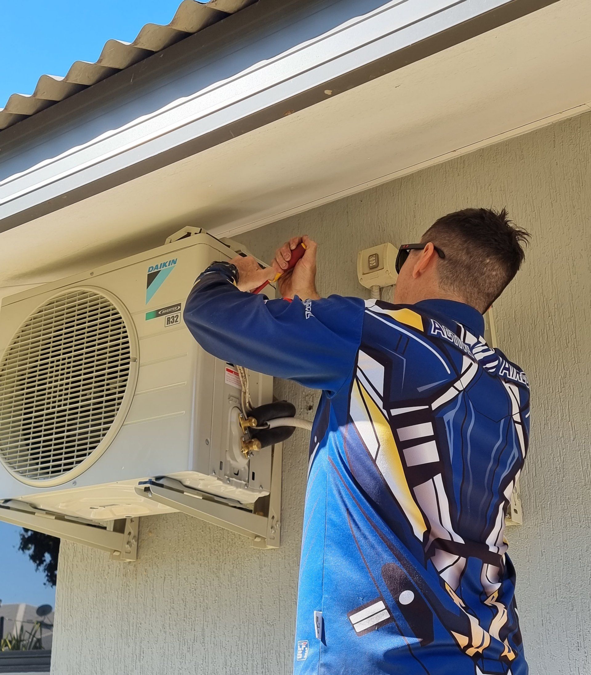 HVAC technician works on a Daikin air conditioner unit mounted on a building exterior. — Active Airconz in Toowoomba, QLD