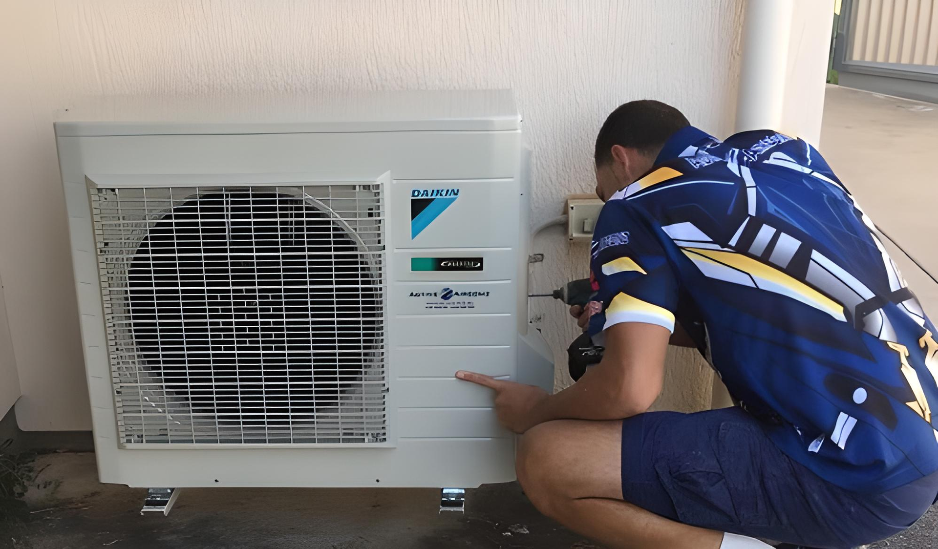 Man installing an air conditioner unit outside a building. He is using a drill. — Active Airconz in Townsville, QLD