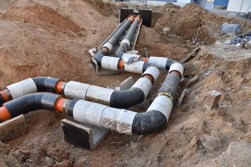 Two Long Pipes Are Laying in the Dirt — T. Woods Plumbing in Bathurst, NSW