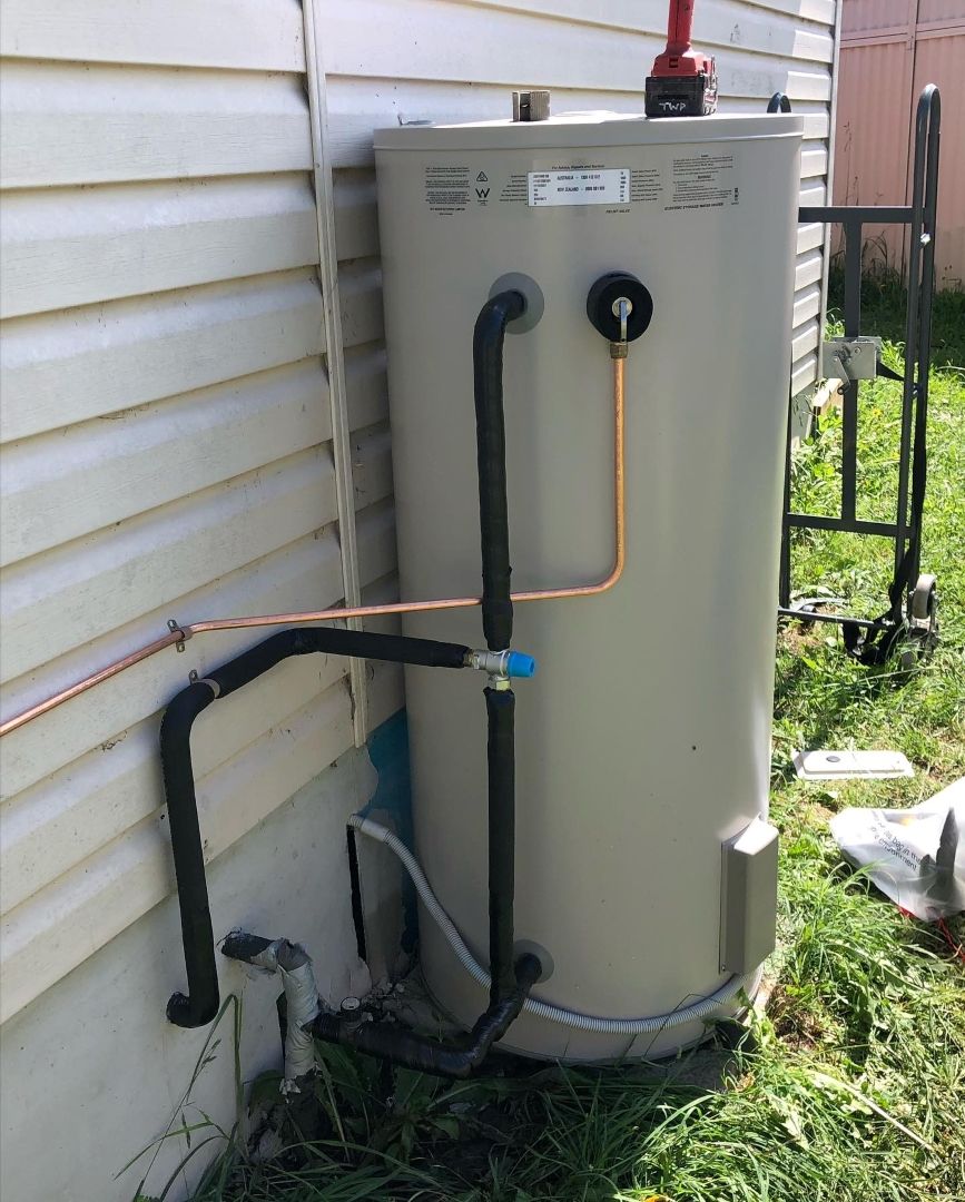 A Water Heater is Attached to the Side of a House — T. Woods Plumbing in Bathurst, NSW