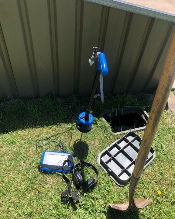 A Hose, Headphones, and a Shovel Are Sitting on the Grass Next to a Fence — T. Woods Plumbing in Bathurst, NSW