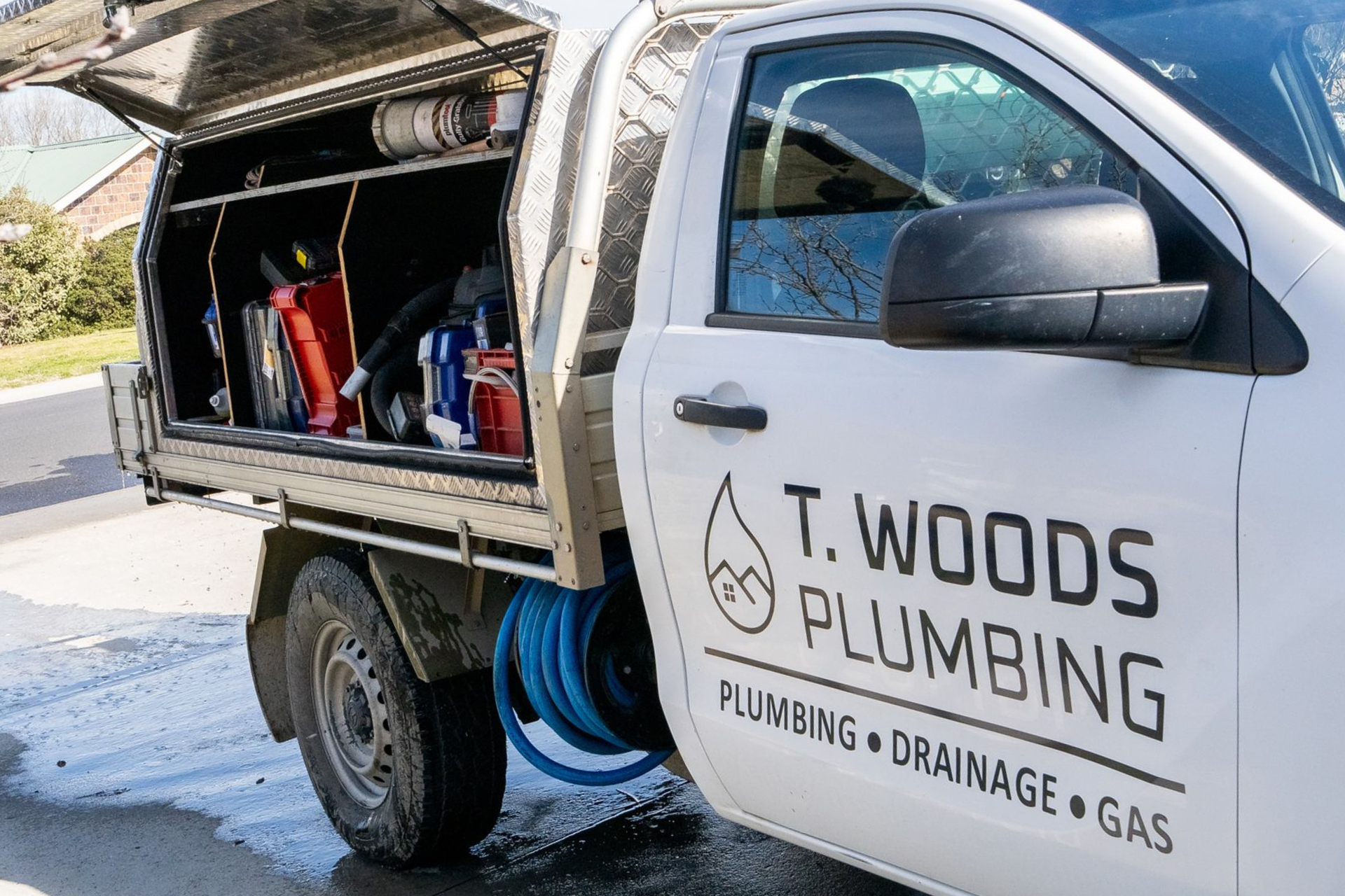 White T. Woods Plumbing truck with open service compartment, parked outdoors on a sunny street. — T. Woods Plumbing in Bathurst, NSW