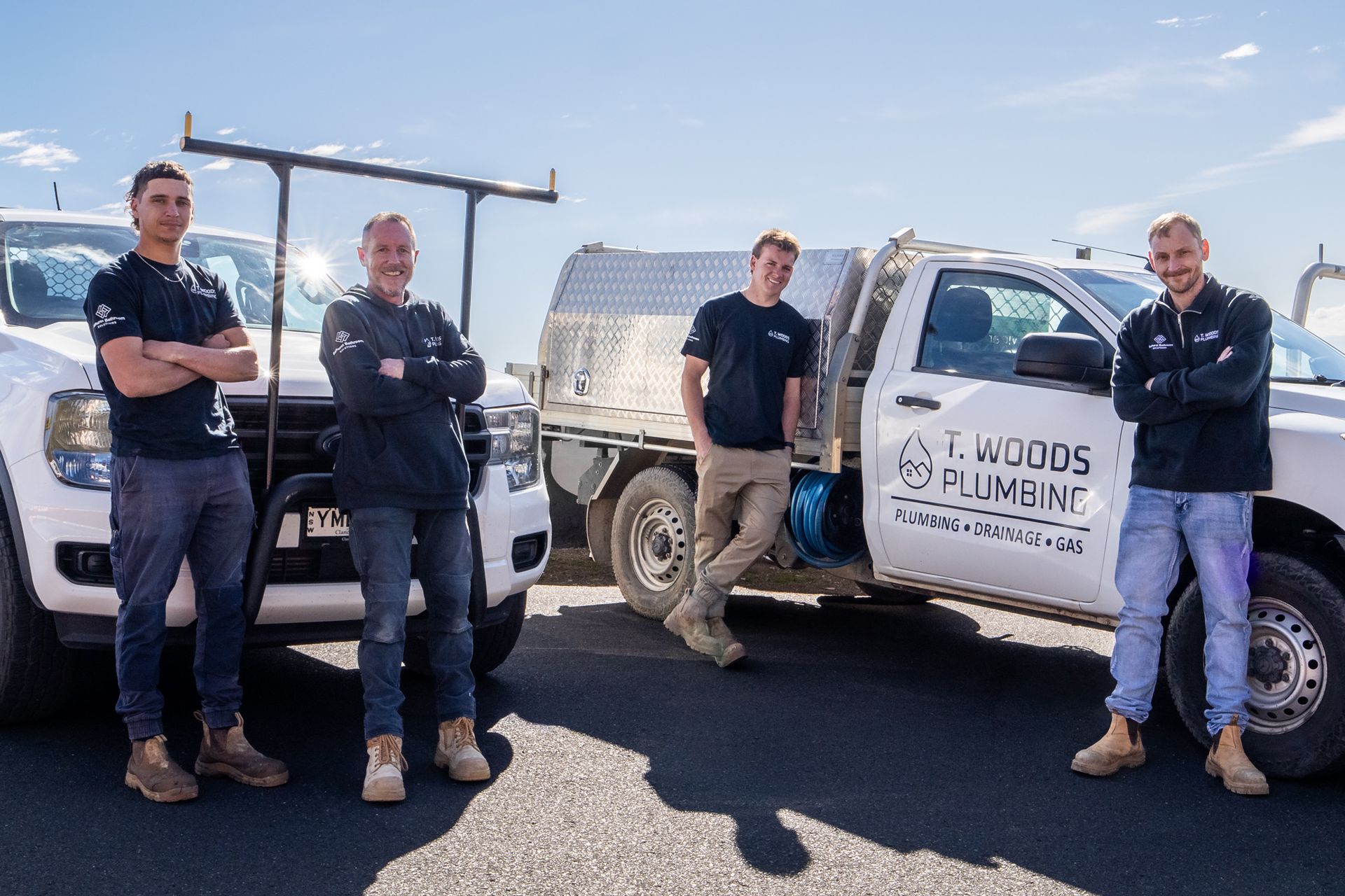 Two workers stand beside a white utility truck in a sunny industrial lot. — T. Woods Plumbing in Bathurst, NSW