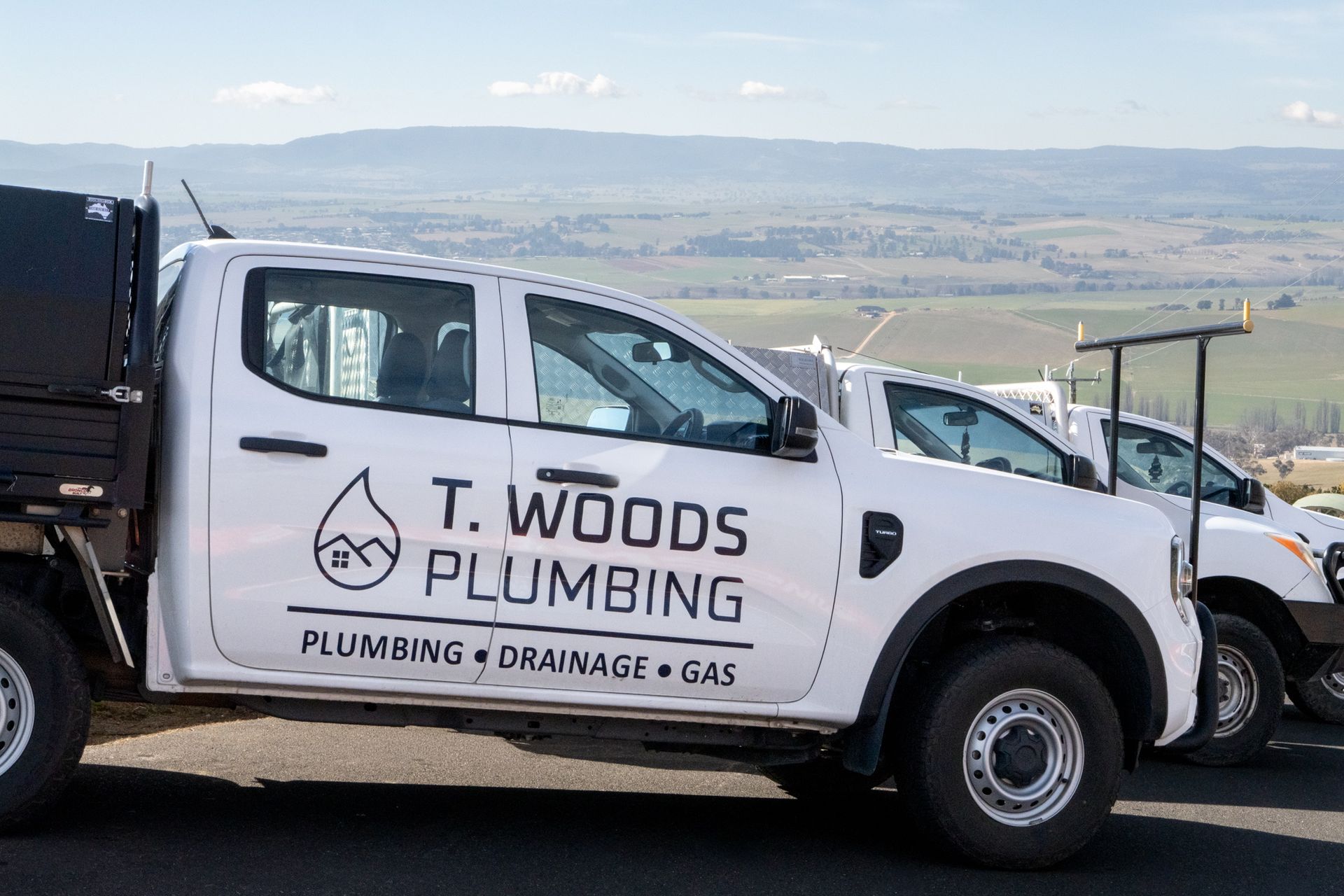 White Wood Plumbing truck parked outdoors with mountains in the background — T. Woods Plumbing in Bathurst, NSW